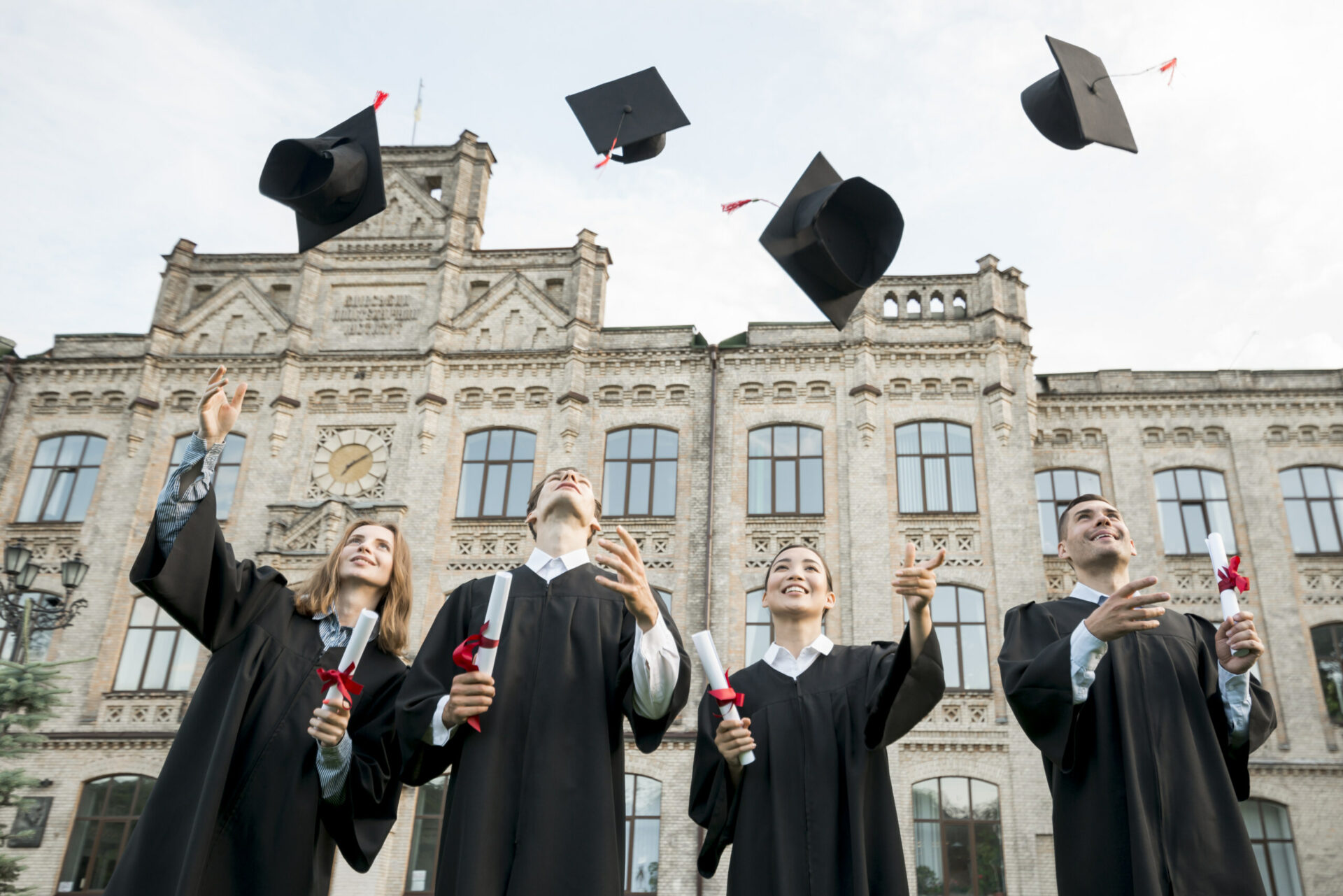 Four person throwing graduation hat happily